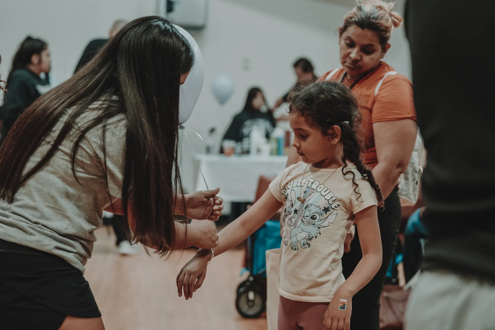 A volunteer handing a balloon to a young girl