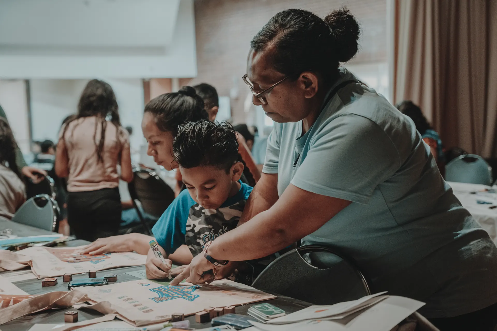 A community member helping a child make papel-picado-style art